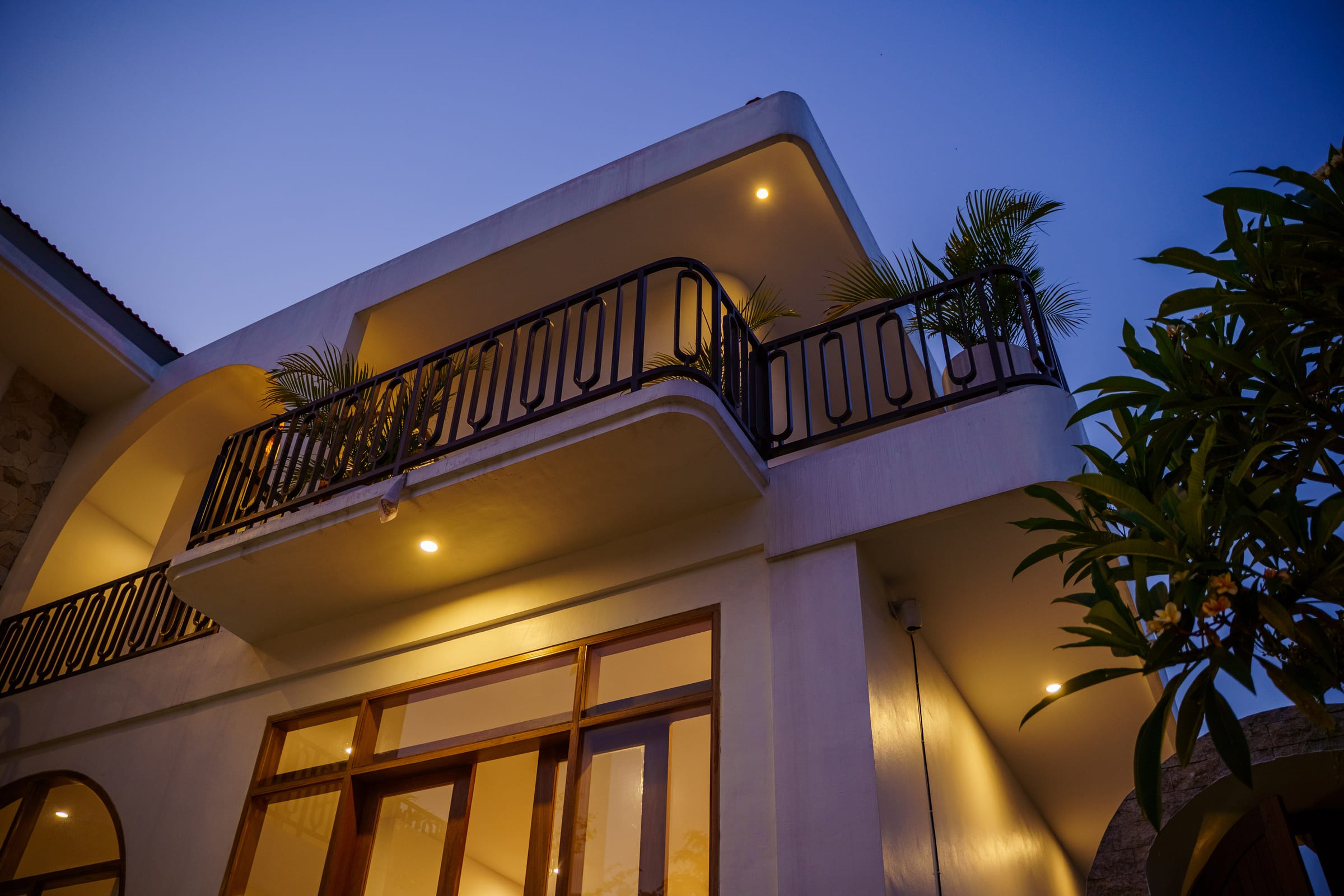 Casa Aurea villa at dusk, with a curved balcony and warm lights against a deep blue sky